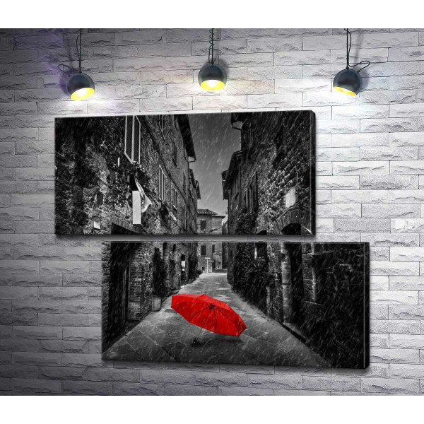 Червона парасолька лежить на дощовій вулиці старого міста