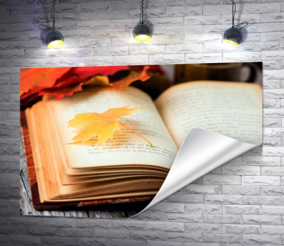 Желтый кленовый листик лежит на странице книги