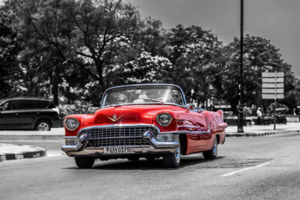 Красный Cadillac Eldorado едет по широкой городской дороге