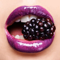 Сочная ягода ежевики между сияющими пурпурными губами