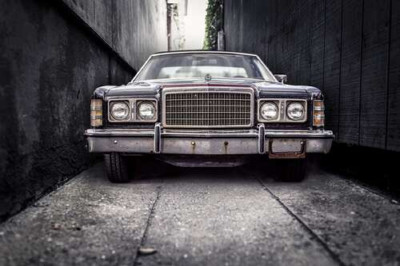 Старый автомобиль Ford LTD стоит в узком переулке