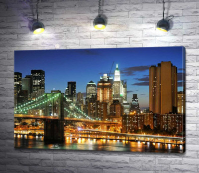 Бруклинский мост (Brooklyn Bridge) исчезает между вечерними небоскребами