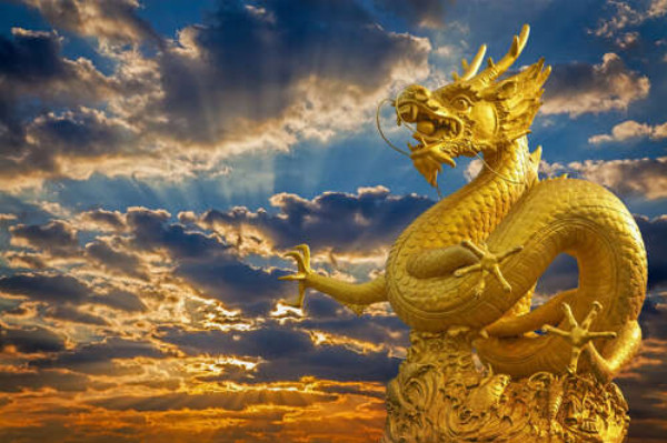 Золотая статуя китайского дракона в лучах солнца