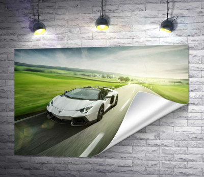 Белый Lamborghini Aventador Roadster несется мимо зеленых полей