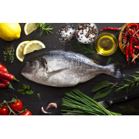 Свежая рыба дорадо в окружении овощей и специй
