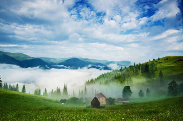 Маленькое поселение в горной долине покрыто белым туманом