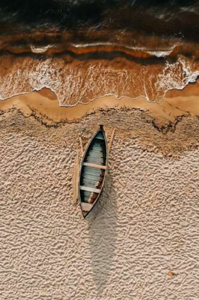 Одинокая лодка на песчаном берегу океана