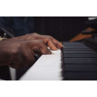 Пальцы афроамериканца играют на рояле