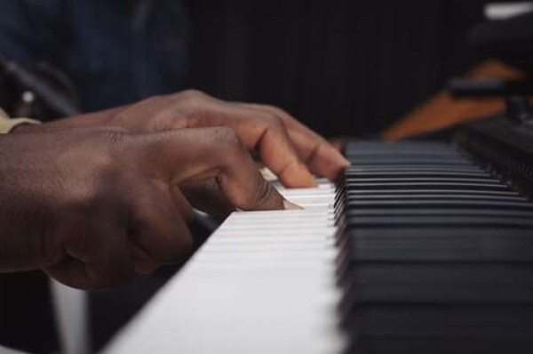 Пальцы афроамериканца играют на рояле