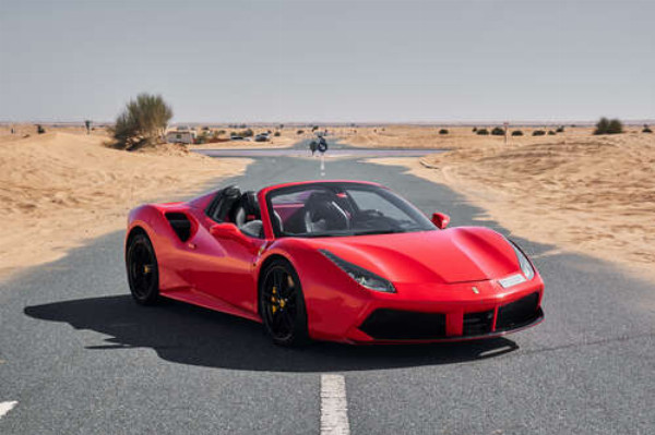 Красный автомобиль Ferrari 488 Spider на пустынной дороге