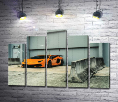 Оранжевый автомобиль Lamborghini Aventador возле ангара