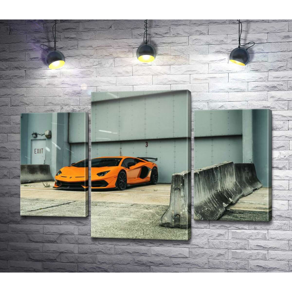 Помаранчевий автомобіль Lamborghini Aventador біля ангара