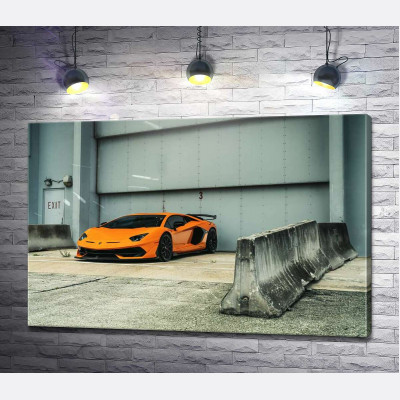 Помаранчевий автомобіль Lamborghini Aventador біля ангара