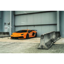 Помаранчевий автомобіль Lamborghini Aventador біля ангара