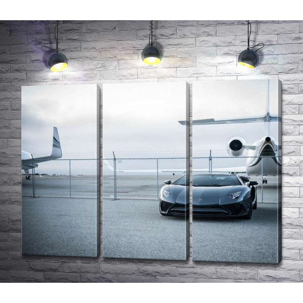 Чёрный автомобиль Lamborghini Aventador на фоне самолетов
