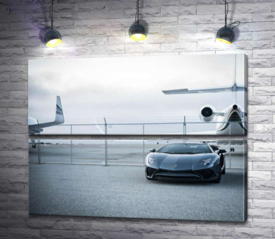 Чёрный автомобиль Lamborghini Aventador на фоне самолетов