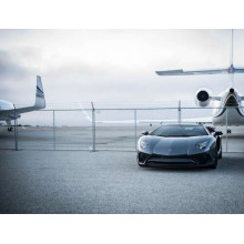 Чорний автомобіль Lamborghini Aventador на фоні літаків