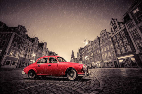 Красный ретро-автомобиль на дождливой мостовой Вроцлава