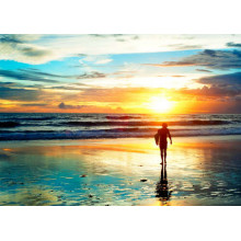 Серфер на пляжі залитому фарбами заходу сонця