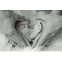 Крохотные ножки младенца в руках мамы и папы