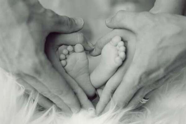 Крохотные ножки младенца в руках мамы и папы