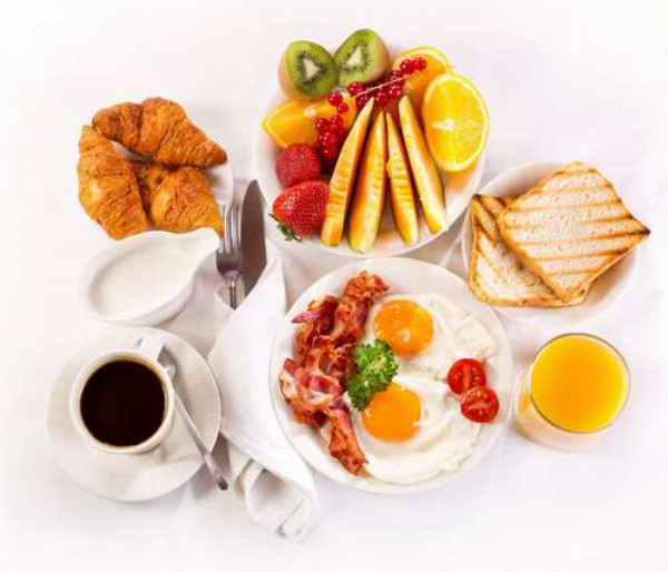 Сытный завтрак из яичницы, бекона, фруктов и выпечки