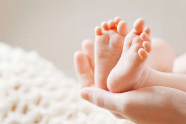 Крохотные ножки младенца на маминой ладони