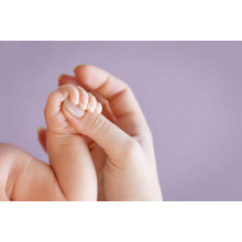 Маленька долонька немовляти обхопила палець мами