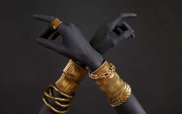 Скрещенные темные руки с золотыми украшениями