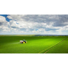 Одинокий трактор в зеленом поле