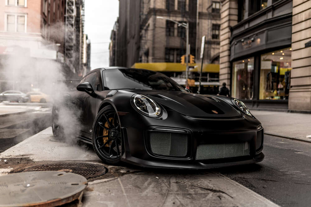 картина-постер Угольно-черный автомобиль Порше (Porsche) 911 среди улицы старого города