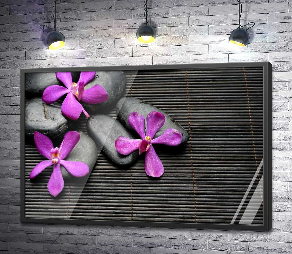 постер Яскраві квіти орхідей на чорному камінні та бамбуковому килимі