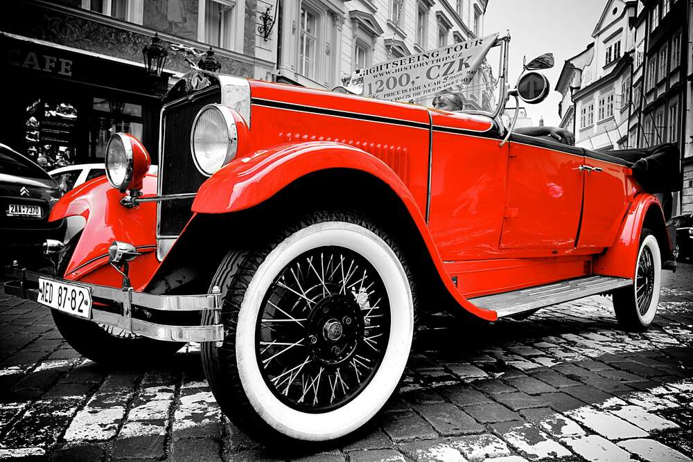 картина-постер Ретро-автомобиль сверкает горяще-красным бампером на улице старого города