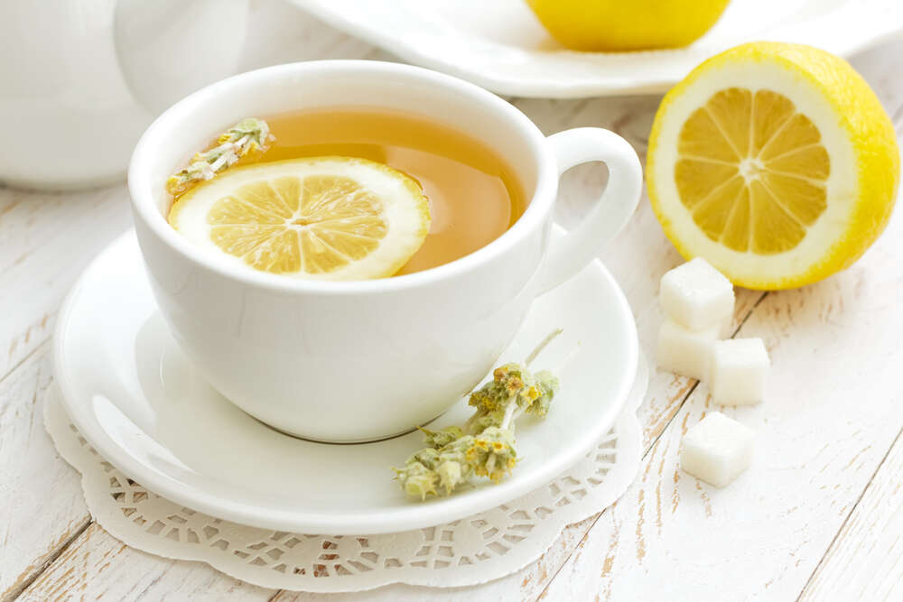 картина-постер Контраст жовтого та білого у чашці лимонного чаю із засушеними квітами полину