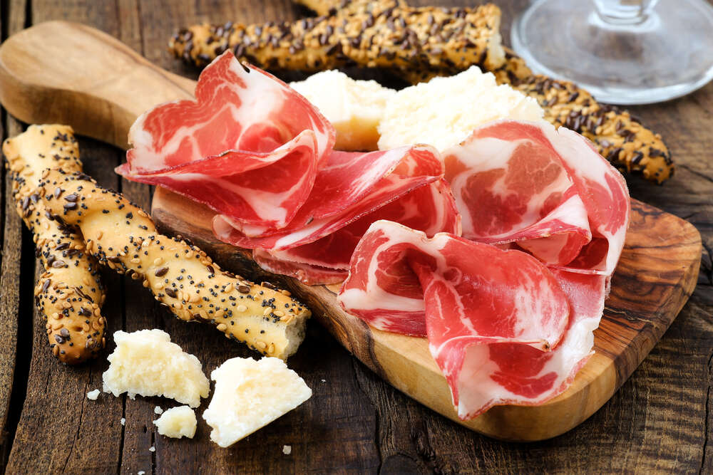 картина-постер Прозорі скибочки іспанського хамону з традиційними італійськими хлібними паличками грисині та шматочками білого сиру