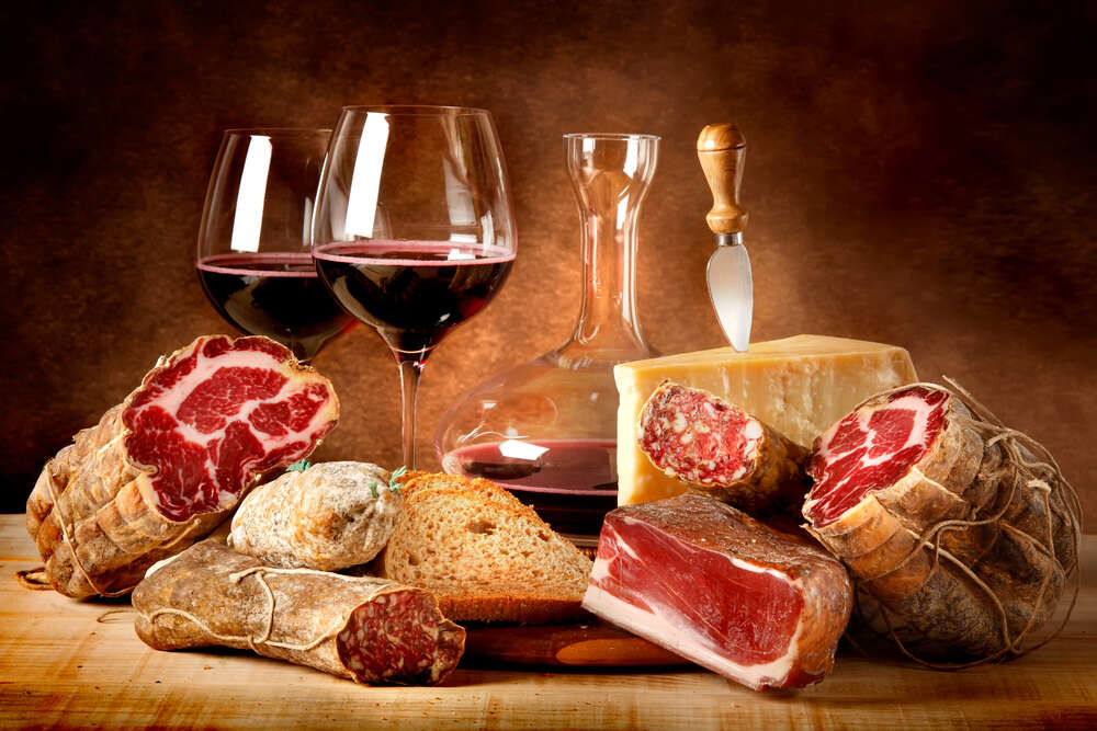 картина-постер Насыщенное красное вино в окружении вяленого мяса с сыром и ломтиком хлеба