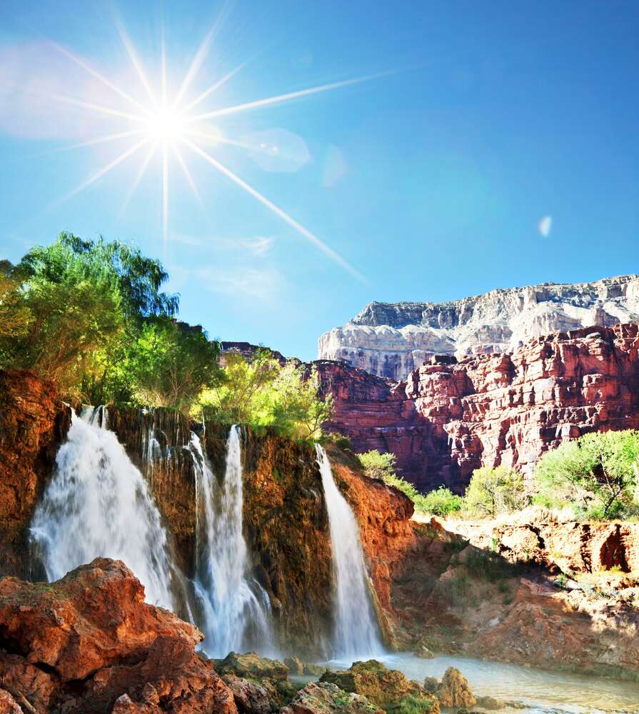 картина-постер Висушені сонцем скелі височіють над водопадом з живильною вологою