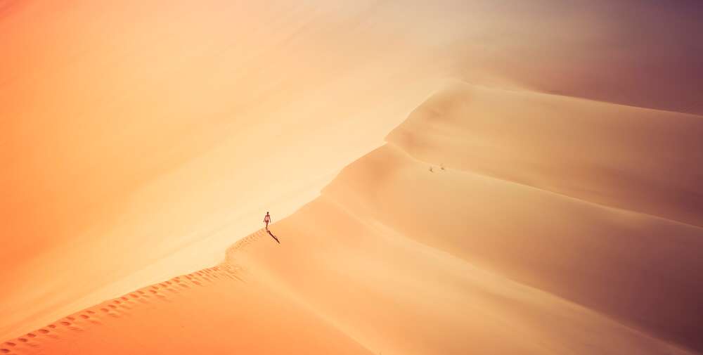 картина-постер Одинокий силуэт человека, идущего по гребню дюны в бескрайней пустыне