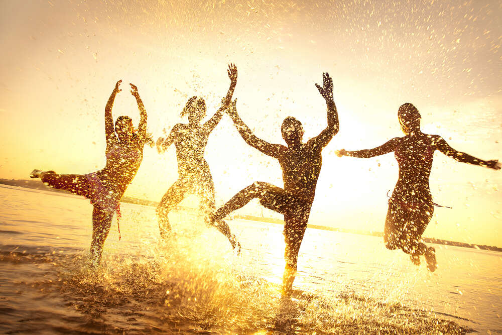 картина-постер Силуэты счастливых людей в лучах солнца и брызгах воды