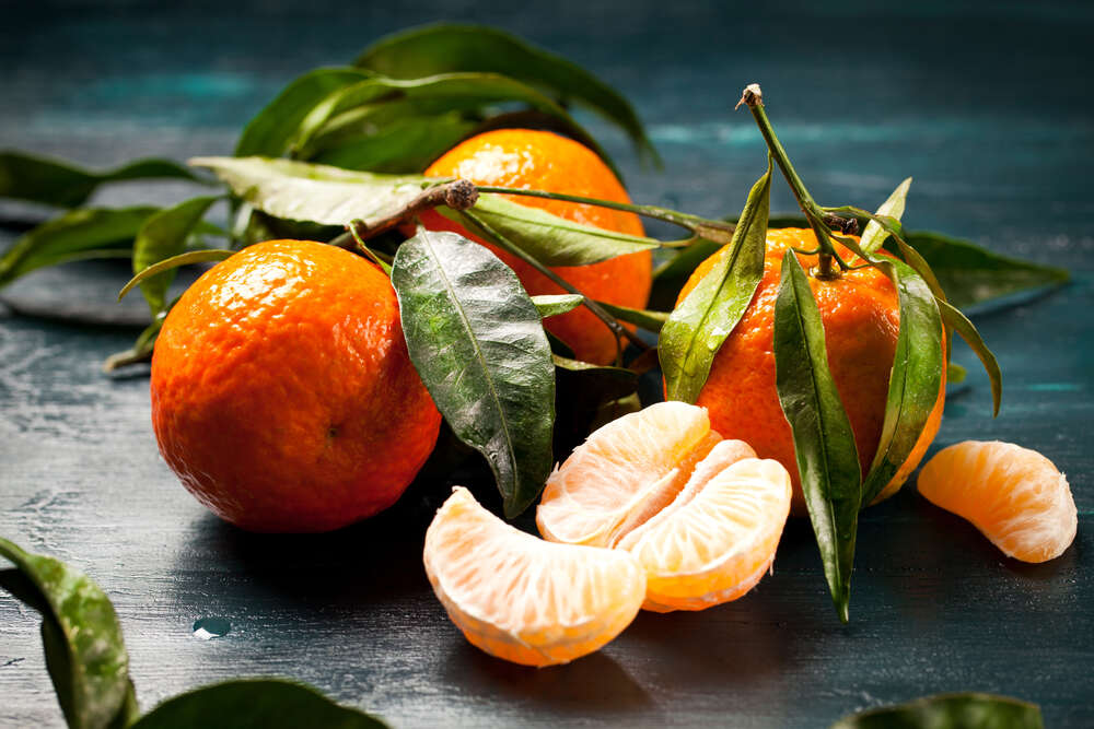 картина-постер Оранжевые поверхности пахучих мандаринов под зеленью листочков
