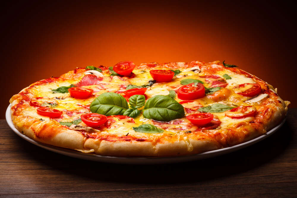 картина-постер Пышный слой теста в пицце, украшенной слайсами помидоров и базиликом