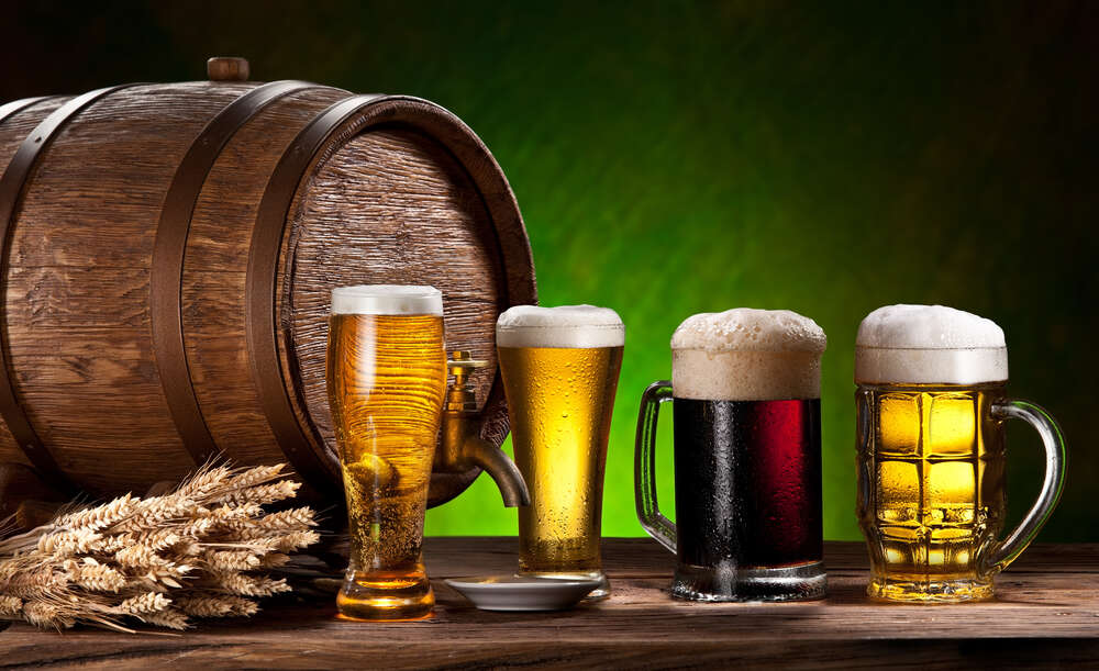 картина-постер Різні сорти пива піняться в прозорих келихах біля бочки