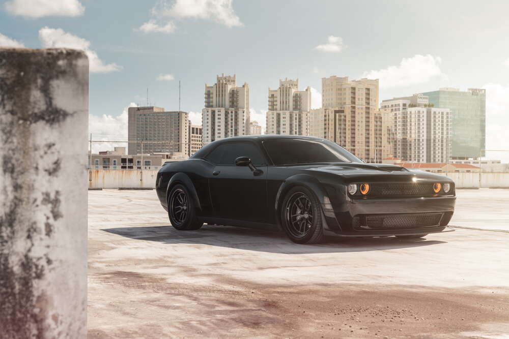 картина-постер Черный автомобиль Dodge Challenger Hellcat на фоне домов