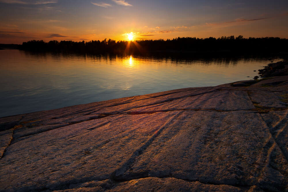 картина-постер Вечірнє сонце кидає проміння на кам'яний берег річки