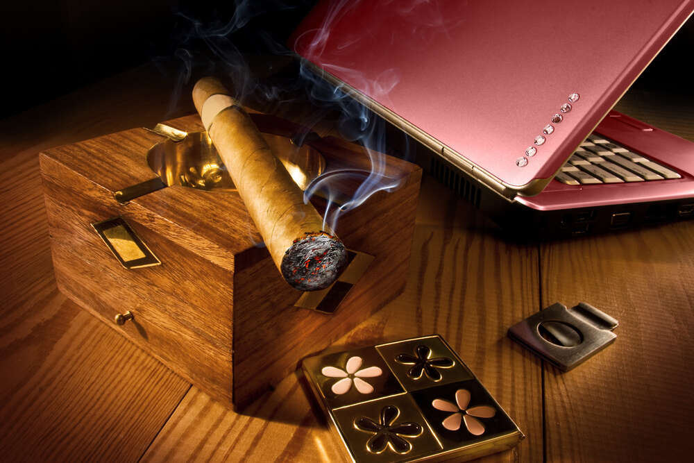 картина-постер Толстая сигара пускает дым на перламутровую поверхность ноутбука