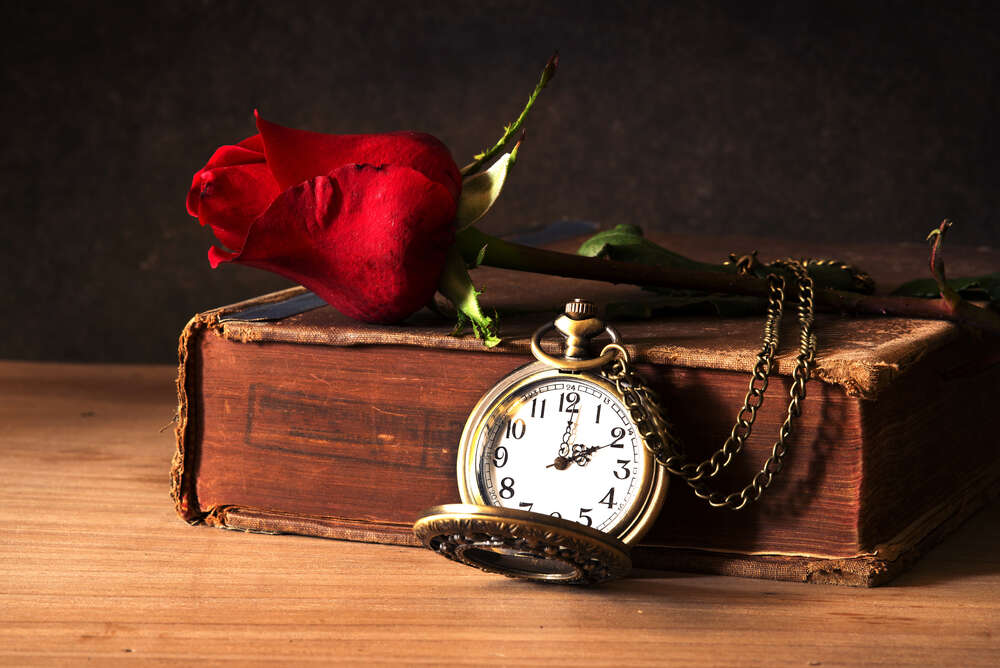 картина-постер Старовинна книга прикрашена кишеньковим годинником та бутоном троянди