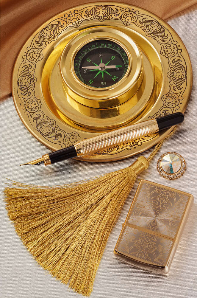картина-постер Компас на золотій таці поряд із вишуканою ручкою та дорогоцінною запальничкою