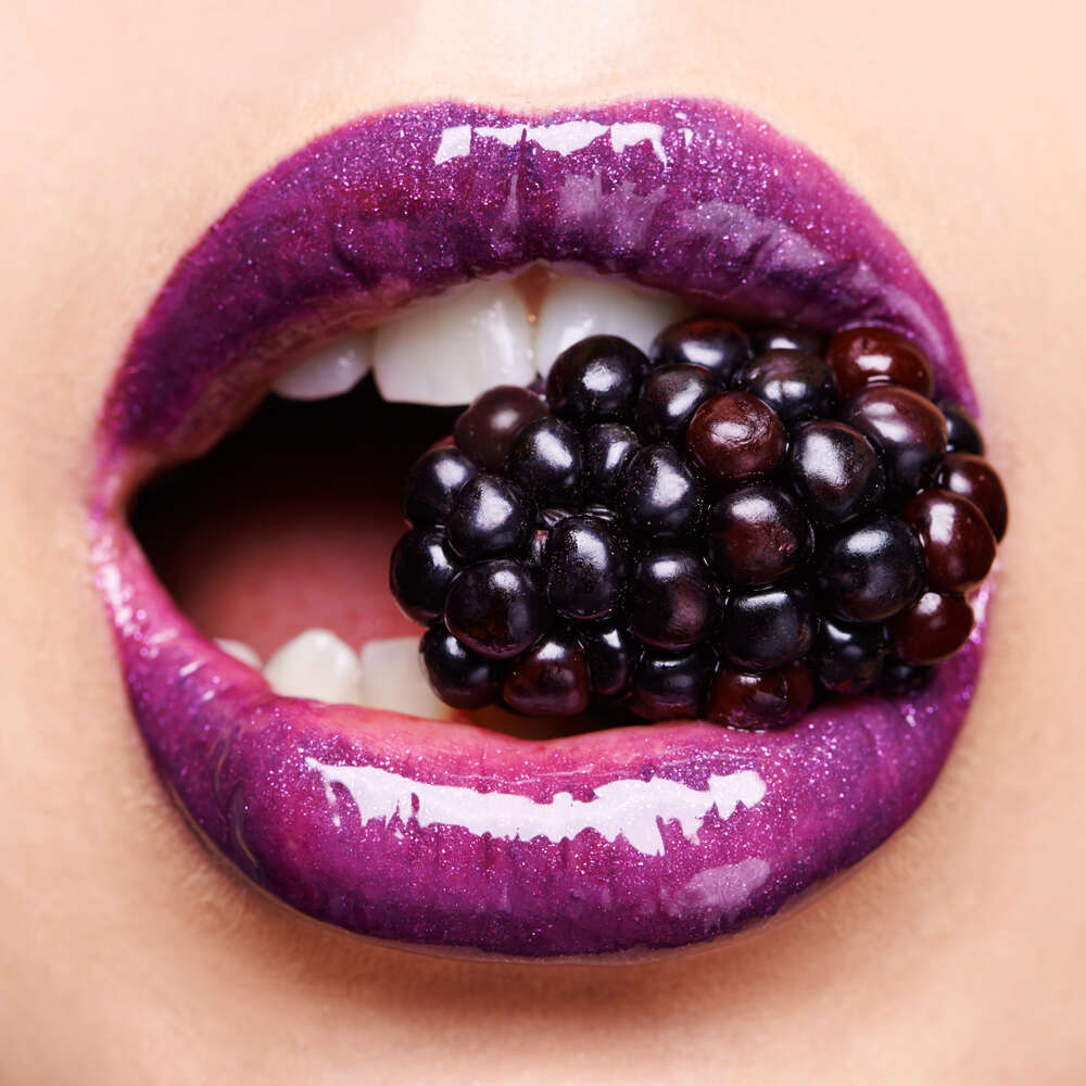 картина-постер Соковита ягода ожини між сяючих пурпурових губ