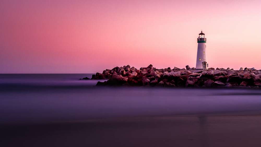 картина-постер Розовое небо окрашивает белые стены маяка на каменистом берегу