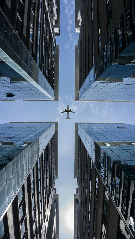 картина-постер Самолет в центре симметрии стеклянных небоскребов